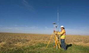 Land surveyor using GPS equipment during topographic surveys in open terrain