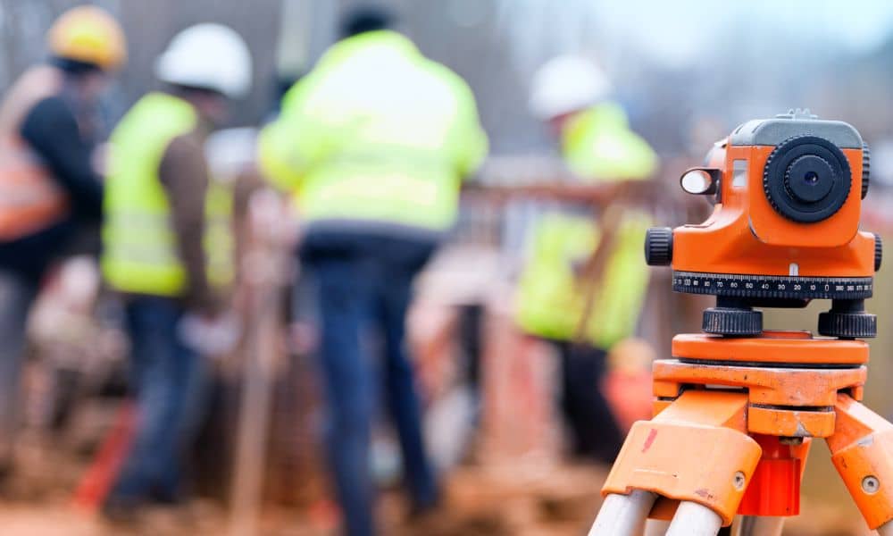 Topo survey equipment set up on a construction site in Lehi with surveyors working in the background.
