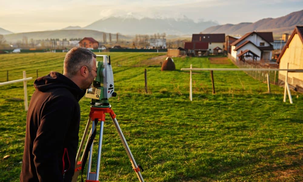 A licensed surveyor using a total station to confirm boundaries and site conditions during an ALTA Land Title Survey before property closing