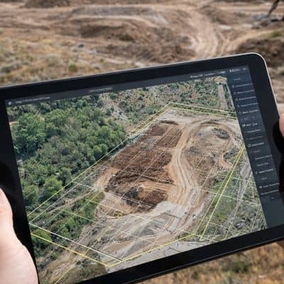 Construction site drone map tablet - ALTA SURVEY Utah Aerial mapping displayed on a tablet showing site boundaries, grid overlays, and excavation progress