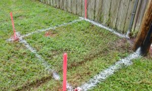 Boundary survey markers and stakes showing a property corner near a residential fence