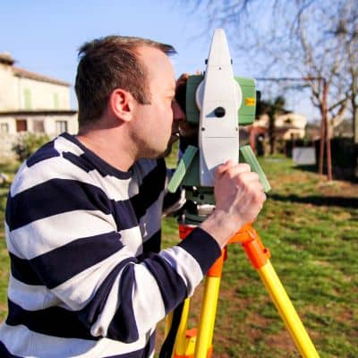 Licensed surveyor performing a boundary survey with a total station instrument