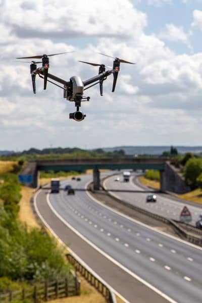 Drone flying above a freeway capturing aerial data for a drone survey of construction progress and roadway conditions